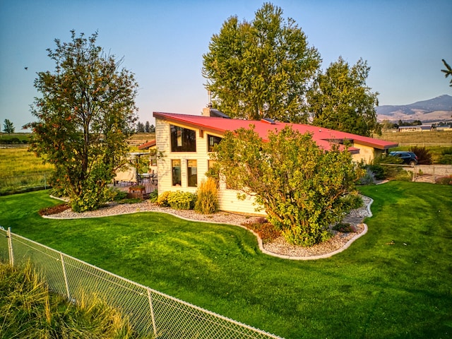 back of house with a mountain view and a lawn