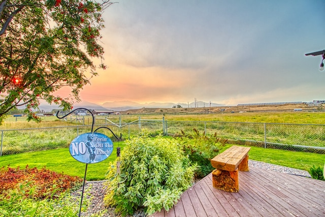 deck at dusk featuring a lawn and a rural view