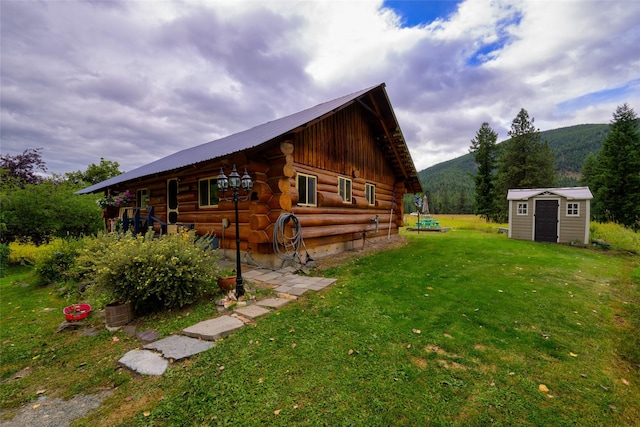 510 Johnson Ln, Superior, MT 59872 - view of property exterior featuring log siding, a mountain view, an outbuilding, a shed, and a lawn