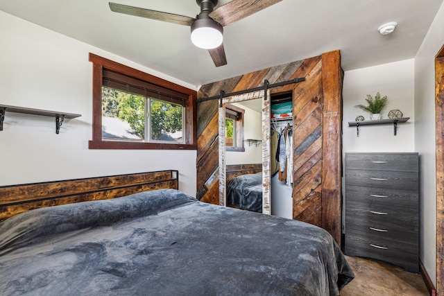 bedroom with ceiling fan, wood walls, and a closet