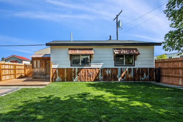 rear view of house featuring a wooden deck and a lawn