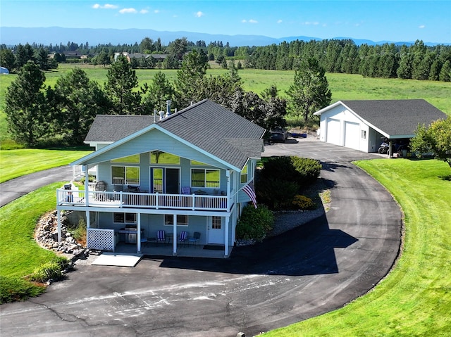 view of front facade featuring a mountain view, a porch, a balcony, a garage, and an outdoor structure