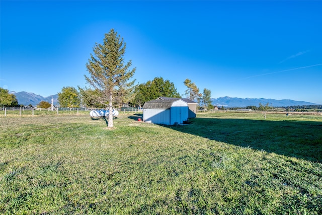 view of yard with a shed, a rural view, and a mountain view