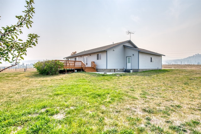 back of property featuring a wooden deck and a yard