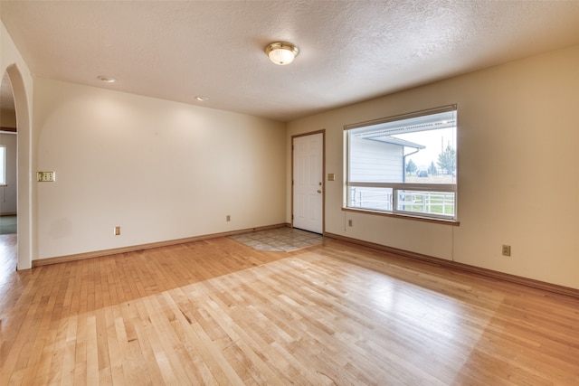 spare room featuring light wood-type flooring and a textured ceiling