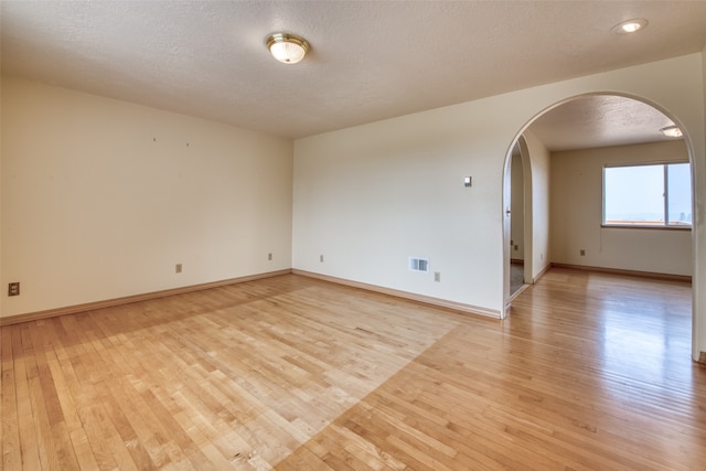 unfurnished room with a textured ceiling and light hardwood / wood-style floors