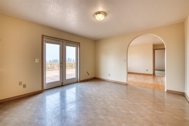 empty room featuring light wood-type flooring, a textured ceiling, and french doors