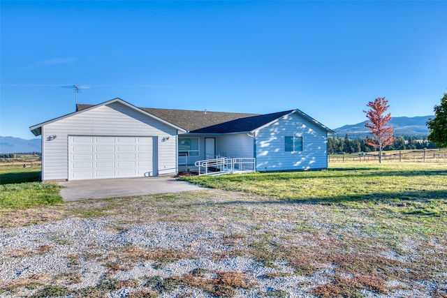 ranch-style home featuring a mountain view, a rural view, a garage, and a front lawn