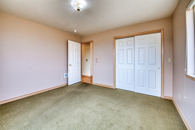 unfurnished bedroom with a textured ceiling, carpet, and a closet