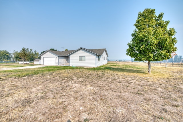 view of front of house with a front lawn, a rural view, and a garage