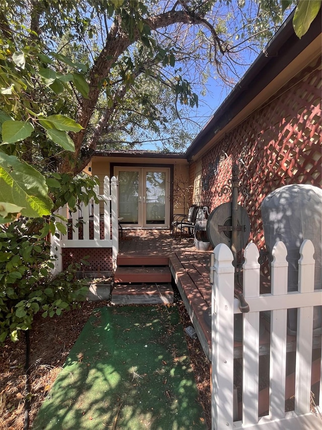 view of exterior entry with a wooden deck and french doors