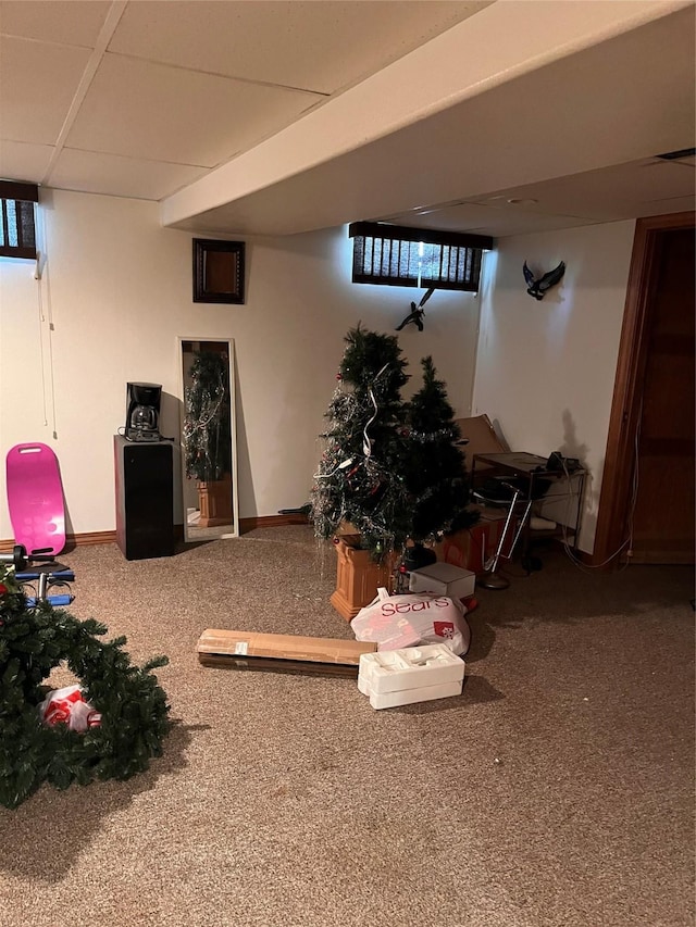 below grade area with carpet flooring, a paneled ceiling, and baseboards