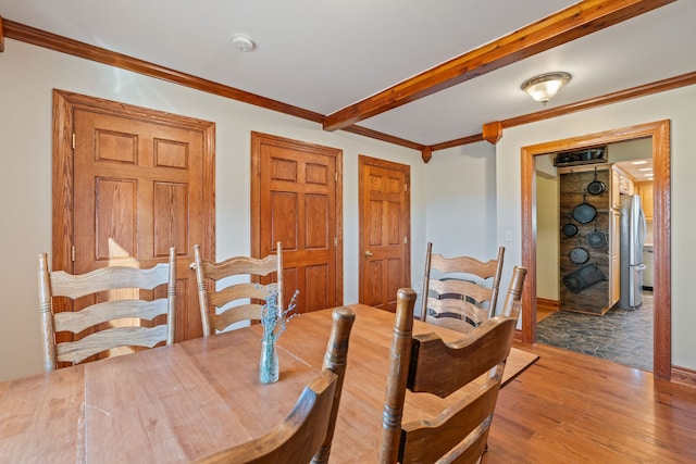 dining area featuring ornamental molding, beamed ceiling, and light hardwood / wood-style flooring