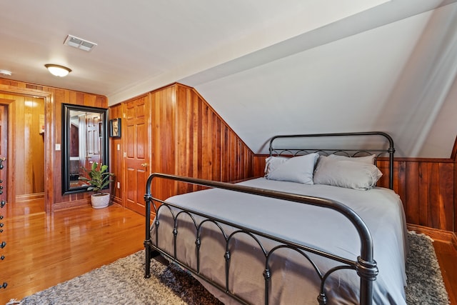 bedroom with wood walls and light hardwood / wood-style flooring