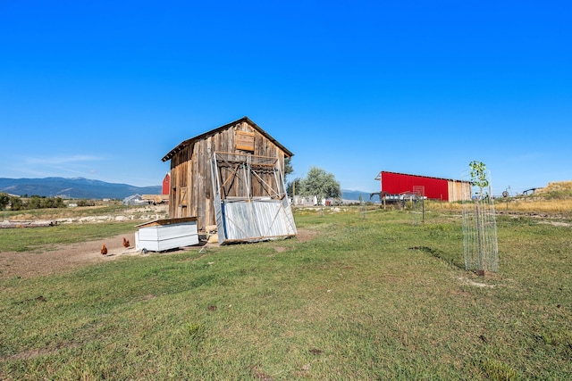 view of outbuilding featuring a yard, a rural view, and a mountain view