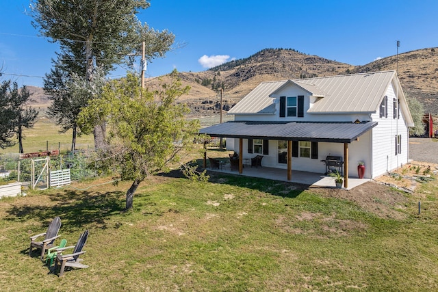 rear view of house featuring an outdoor fire pit, a mountain view, a lawn, and a patio area