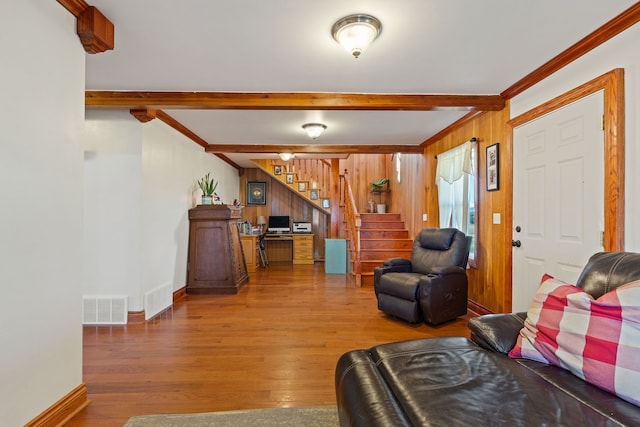 living room featuring beamed ceiling, wood walls, hardwood / wood-style flooring, and crown molding