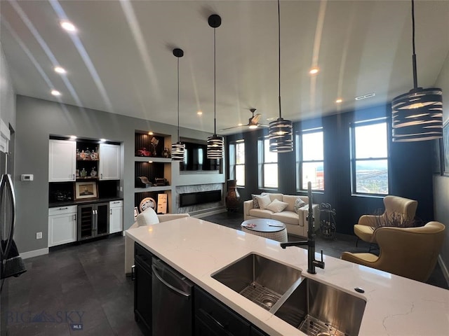 kitchen featuring light stone countertops, black dishwasher, a premium fireplace, hanging light fixtures, and ceiling fan