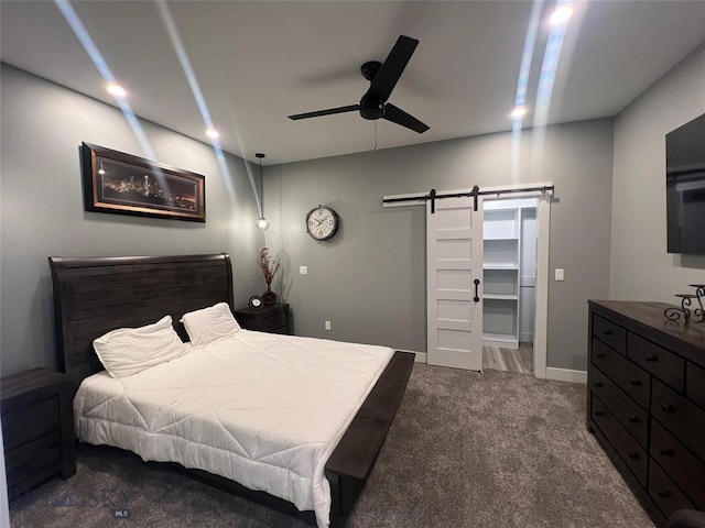 bedroom with ceiling fan, a barn door, and carpet floors