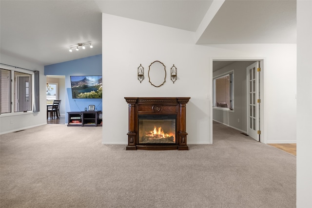 unfurnished living room featuring vaulted ceiling, carpet, and track lighting