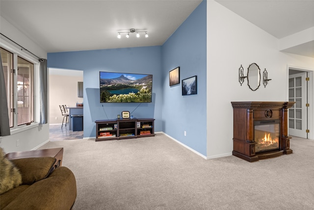 living room featuring vaulted ceiling, carpet flooring, and rail lighting