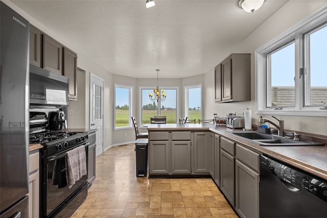 kitchen with sink, a textured ceiling, decorative light fixtures, black appliances, and an inviting chandelier