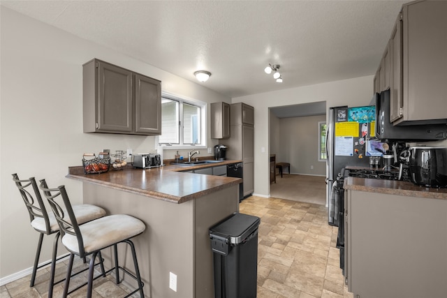 kitchen featuring gray cabinetry, a breakfast bar, sink, kitchen peninsula, and a textured ceiling