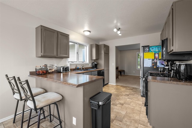 125 Ponderosa Ln, Kalispell, MT 59901 - kitchen with a breakfast bar, a peninsula, light stone finish flooring, dark countertops, and gray cabinetry