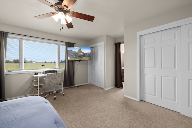 bedroom featuring ceiling fan, multiple closets, and light carpet