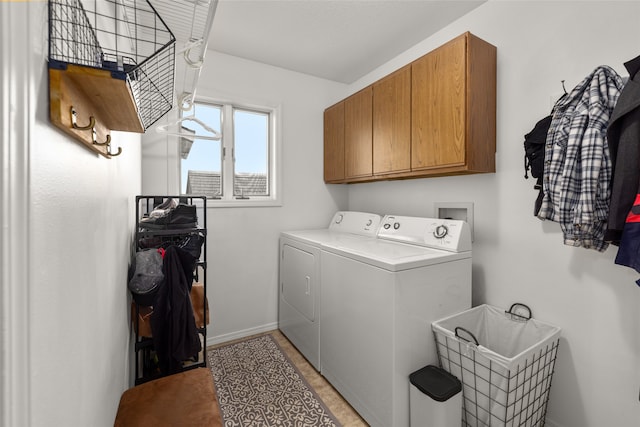 clothes washing area featuring washing machine and dryer, light tile patterned floors, and cabinets