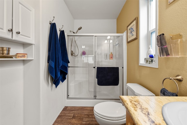 bathroom with hardwood / wood-style floors, vanity, a shower with shower door, and toilet