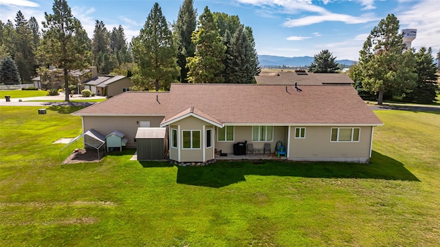 rear view of property featuring a yard, a mountain view, and a patio area