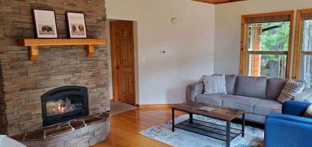 living room featuring plenty of natural light, a stone fireplace, and wood-type flooring