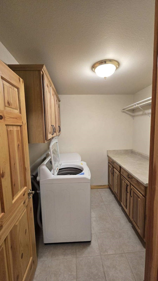 laundry area with a textured ceiling, cabinets, and washer and clothes dryer