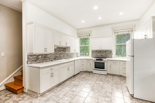 kitchen with white appliances, backsplash, ornamental molding, sink, and white cabinets