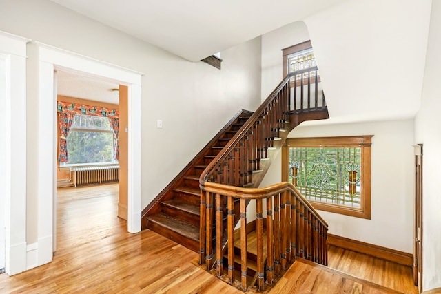 stairway with radiator and hardwood / wood-style flooring