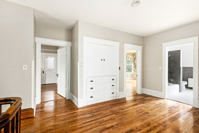 bedroom featuring wood-type flooring, radiator heating unit, and ensuite bath