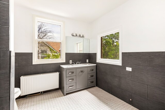 bathroom featuring tile walls, toilet, radiator, and vanity