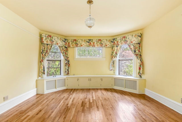 spare room featuring a wealth of natural light, radiator heating unit, and light wood-type flooring