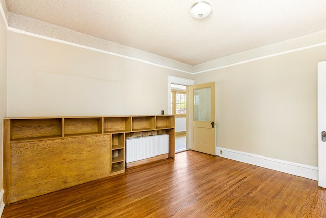 spare room with a textured ceiling, radiator heating unit, and wood-type flooring