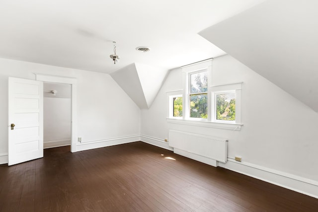 additional living space with lofted ceiling, dark hardwood / wood-style flooring, and radiator heating unit