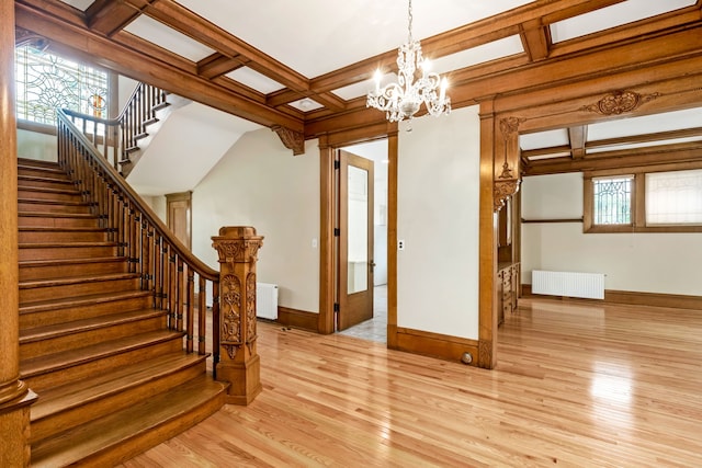 interior space with coffered ceiling, a notable chandelier, light hardwood / wood-style flooring, radiator, and beam ceiling