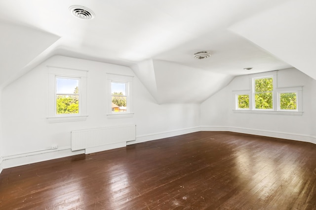 additional living space with lofted ceiling, dark hardwood / wood-style flooring, a wealth of natural light, and radiator