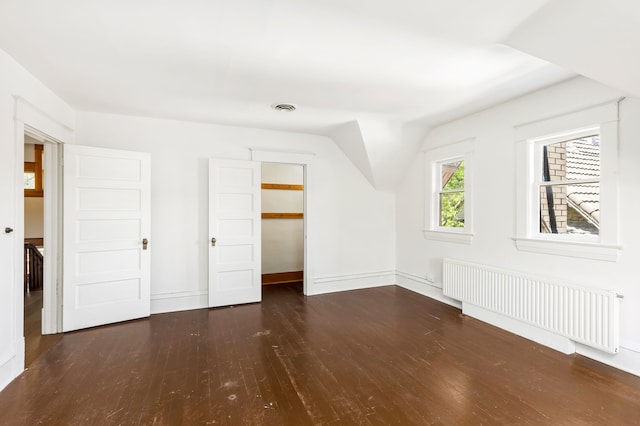 additional living space with radiator, vaulted ceiling, and dark wood-type flooring