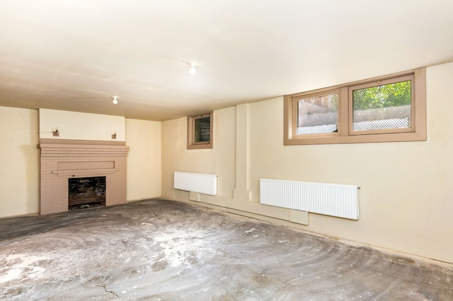 unfurnished living room featuring radiator and a brick fireplace