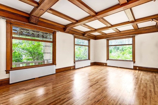 spare room with coffered ceiling, light hardwood / wood-style floors, radiator heating unit, and beam ceiling