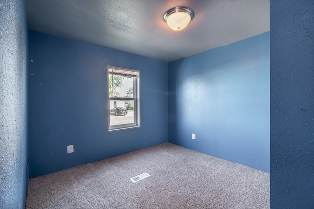 carpeted empty room featuring a textured ceiling