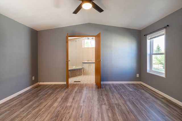 unfurnished bedroom featuring ceiling fan, hardwood / wood-style flooring, vaulted ceiling, and ensuite bath