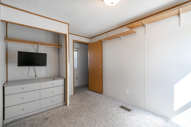 unfurnished bedroom featuring a closet, light colored carpet, and a textured ceiling