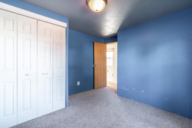 unfurnished bedroom with a closet, a textured ceiling, and carpet floors